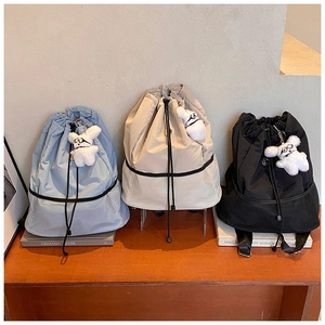 Detailansicht lässiger Nylon-Rucksäcke in Blau, Beige und Schwarz mit Bärenanhänger