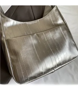 Détail de la texture cuir argenté métallisé et plis verticaux d'un sac à main croissant