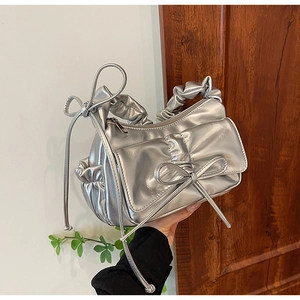 Dettaglio borsa sottobraccio metallizzata argento con fiocco e manico plissettato