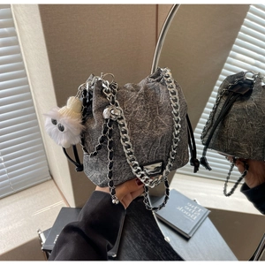 Detail of dark grey denim bucket bag with thick silver chain and plush monster charm