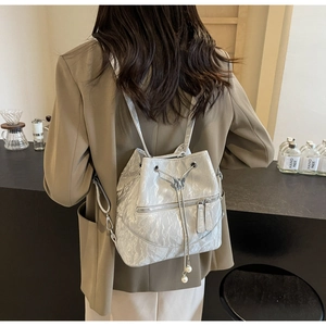 Detail of silver pleated bucket backpack with drawstring closure and pearl pendant charm