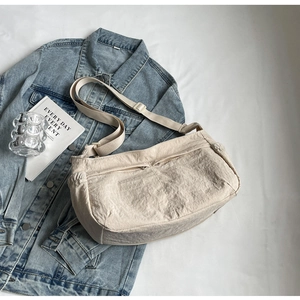 Detail of minimalist beige nylon crossbody bag featuring dual front zipper pockets