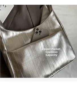 Détail du sac hobo argenté avec texture gaufrée verticale et poche avant pratique