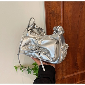 Dettaglio della borsa metallizzata argento con grande fiocco e rifiniture a pieghe