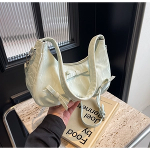 Detail of mint green wrinkled texture handbag featuring elegant bow accents and slim strap