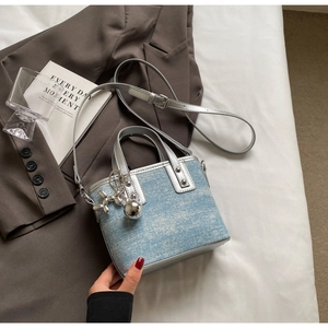 Detail of light blue denim bucket bag with silver leather trim and cute dog charm