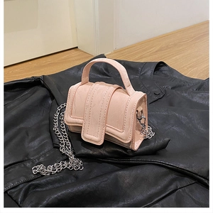 Detail of a light pink mini square handbag with silver chain strap on leather jacket