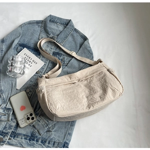 Detail view of beige nylon crossbody bag with multi-pocket structure and adjustable strap