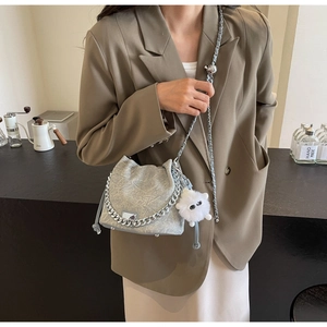 Detail of silver textured bucket bag with metallic chain and plush eye pendant accessory