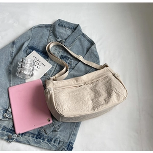 Beige nylon crossbody bag shown with a tablet and denim jacket for daily commute use