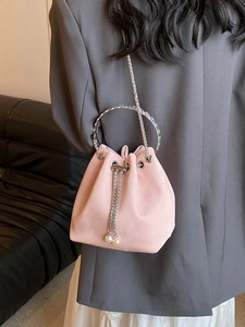 Pink suede bucket bag with silver ring handle and pearl drawstring on grey blazer