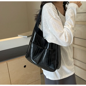 Détail d'un grand sac fourre-tout noir brillant avec texture plissée et poche latérale