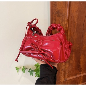 Dettaglio della borsa rossa in vernice con fiocco decorativo e manico arricciato