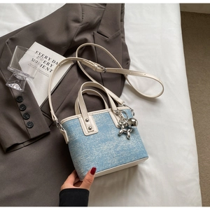 Detail of light blue denim mini tote with white leather trim and silver balloon dog charm