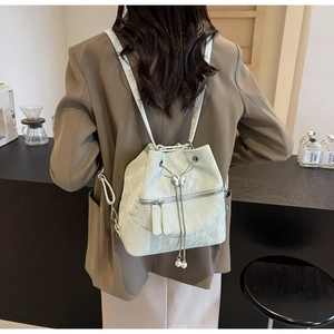 Detail of light green bucket backpack featuring metallic butterfly and pearl charms