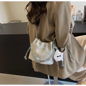 Silver bucket bag with chunky chain and furry monster charm worn with a blazer