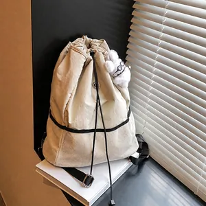 Detalle de la mochila de lona beige con bolsillo de malla y accesorio de amuleto de perro peluche