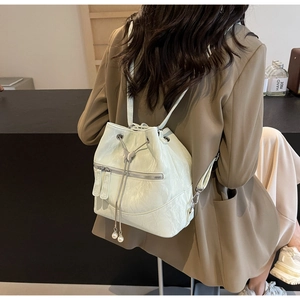 Detail of mint green bucket backpack featuring metallic butterfly and pearl accents