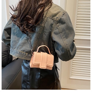 Pink mock-croc mini handbag worn with metal chain strap over a denim jacket