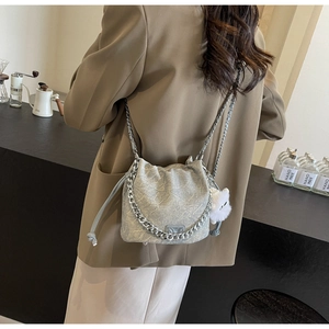 Detail of silver-grey bucket bag with embossed texture and plush cat charm