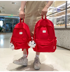 Detail of red canvas backpacks with panda plush pendant and bear logo labels