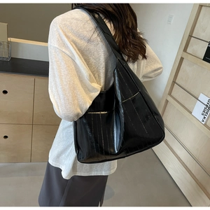Détail montrant la texture en cuir noir brillant plissé sur un sac cabas chic
