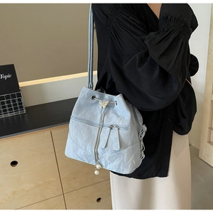 Detail of light blue pleated bucket bag featuring silver butterfly and pearl charms