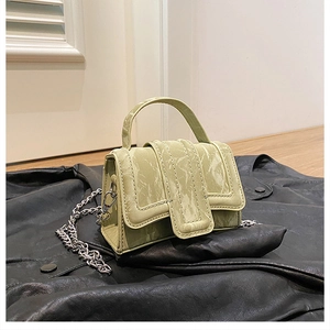 Detail of light green pebble grain leather mini bag with silver chain on black jacket