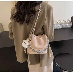 Detail of light brown bucket bag with vintage texture and silver chain strap on a model