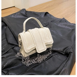 Close-up of cream white mini square bag with unique triple-layer flap and silver chain strap
