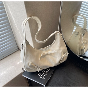 Detailed macro view of cream leather hobo bag with textured bow accents and silver zipper