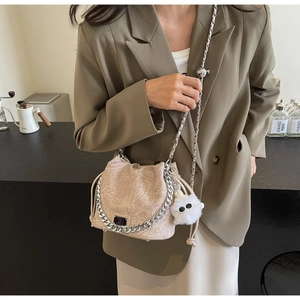 Detail of beige bucket bag with marble pleats, silver chain and plush monster charm