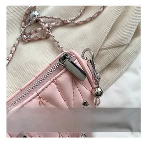 Detail of pink quilted crossbody bag showing silver zipper and heart charm tassel