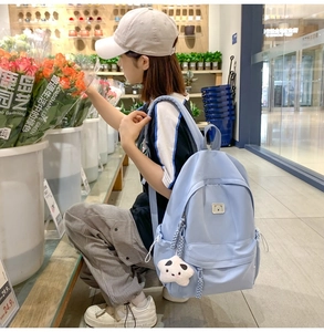 Detail of light blue backpack with star plush pendant in a vibrant flower shop setting