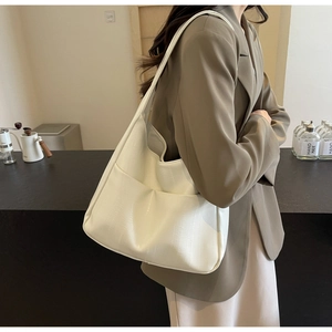 Détail du sac fourre-tout blanc cassé avec texture motif crocodile et grande poche avant