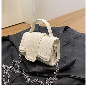 Detail of cream mini handbag featuring marble texture strap and silver chain strap