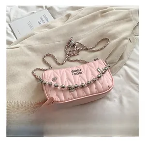 Detailed view of pink quilted handbag with silver chain strap and beaded metal accents