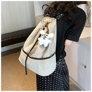 Detail eines beigen Nylon-Kordelzug-Rucksacks mit Netztasche und Plüschbär-Anhänger