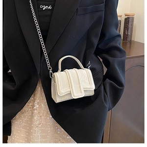 Chic cream mini crossbody bag with metal chain strap styled on a black blazer outfit
