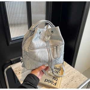 Detail of silver metallic bucket backpack with butterfly buckle and pearl drawstring charms