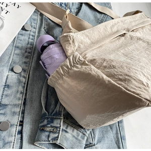 Detail view of water-resistant nylon shoulder bag side pocket with a small umbrella