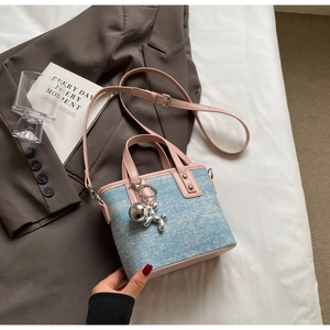Detail of mini bucket bag in blue and white denim with pink handle and silver dog charm