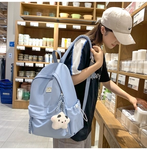 Close-up of light blue nylon backpack with cute bear patch and star plush pendant