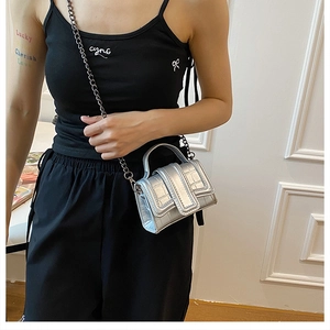 Detail of silver crocodile-pattern mini handbag with metallic chain and handle