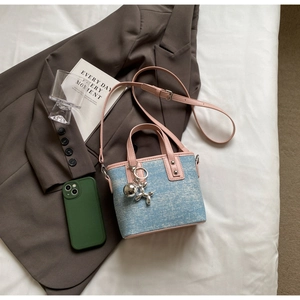 Detail of blue denim bucket bag with pink leather trim and silver balloon dog charm