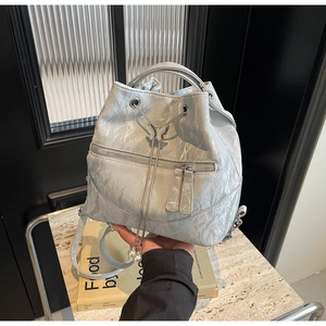 Detail of silver metallic wrinkled backpack with butterfly buckle and pearl drawstrings