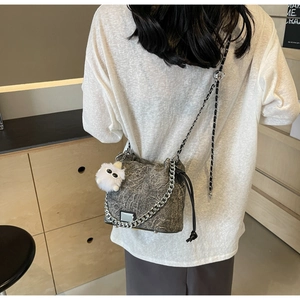 Detail of grey marble textured bucket bag with silver chain and white plush charm