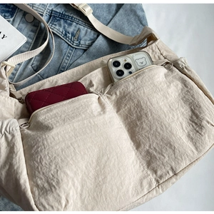 Detailed interior of beige nylon crossbody bag showing spacious storage with wallet and phone