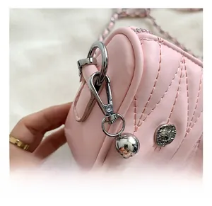 Close-up of pink quilted leather bag with silver metal chain and embossed buckle detail