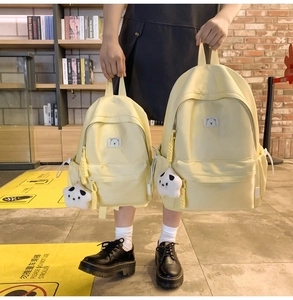 Detail view of large and small cream yellow canvas backpacks with cute panda pendants